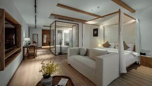 A modern hotel room with a four-poster bed, a sofa, a desk, and a glass-enclosed bathroom. - Leli Villa Designer - Vacation Homestay (Qiandongnan)