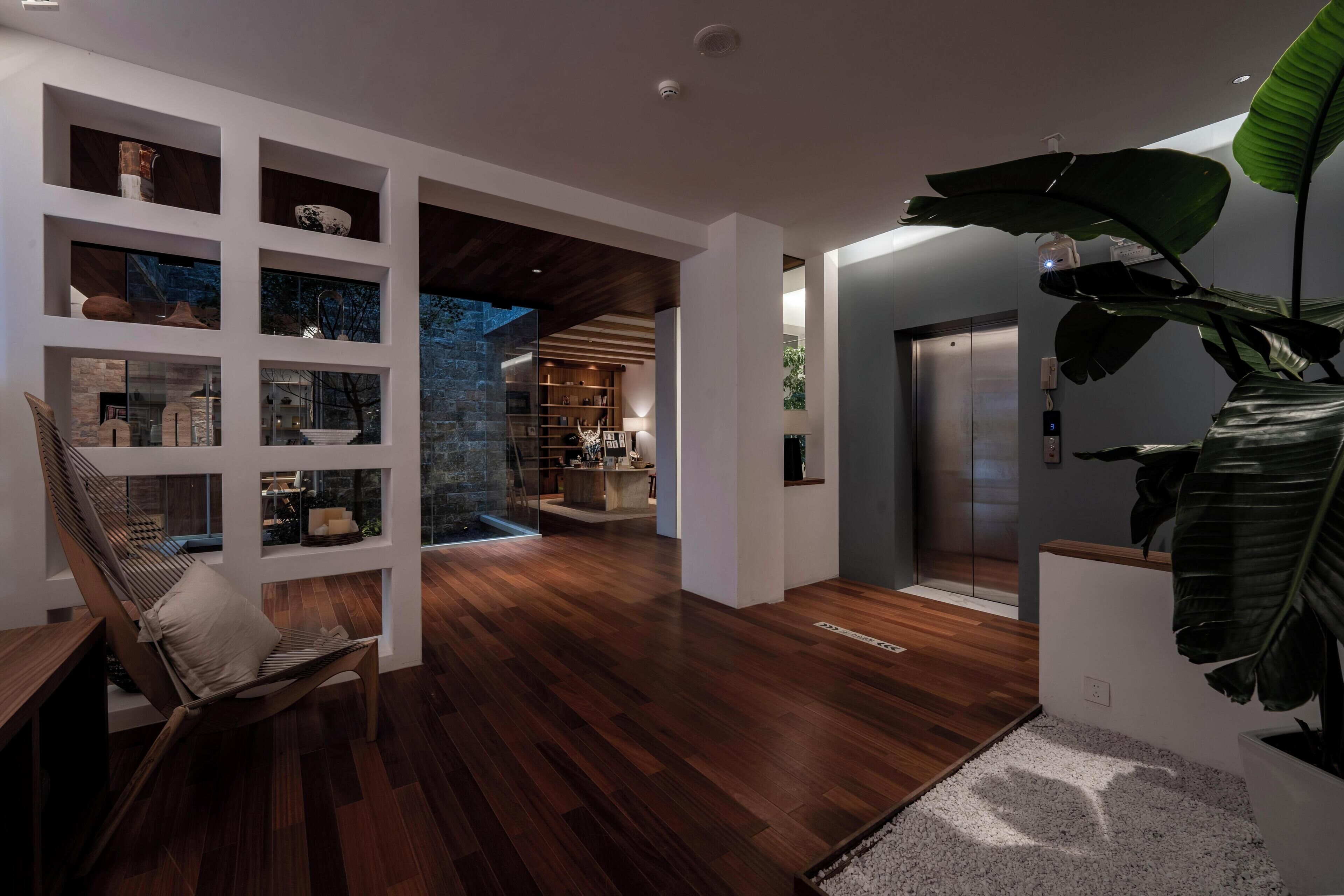 Un intérieur moderne avec un plancher en bois, un fauteuil suspendu en forme de hamac, une bibliothèque et une grande plante.