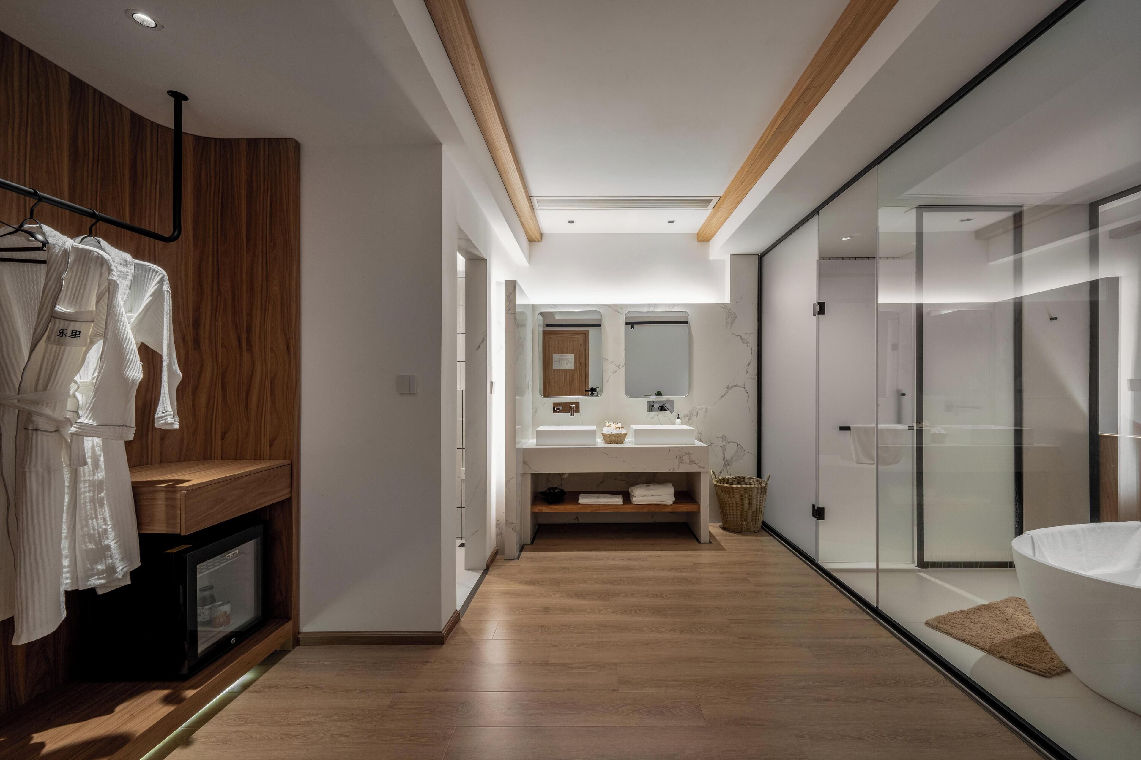 Une salle de bain moderne avec un meuble-lavabo en bois, une cabine de douche en verre et un grand miroir au-dessus du lavabo.
