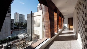 A corridor with a view of a cityscape, a wooden bench, and a table with an umbrella. - Leli Villa Designer - Vacation Homestay (Qiandongnan)