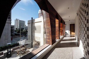 Un pasillo con vistas a la ciudad, un banco de madera y una mesa con sombrilla.