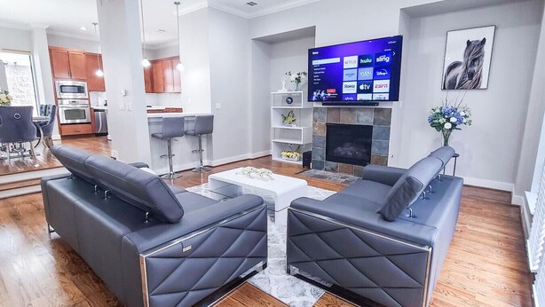 Een moderne woonkamer met een open haard, een flatscreen televisie en een eethoek met barstoelen.