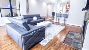Een moderne woonkamer met een hoekbank, een salontafel en een bar met krukken.