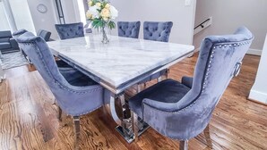 Een eethoek met een marmeren tafel en fluweelzachte stoelen.