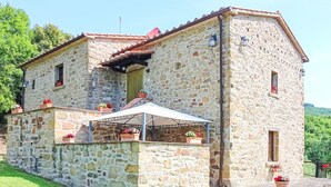 Ein Steinhaus mit Balkon, überdachter Terrasse und Blumentöpfen.