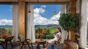 Quarto com uma grande janela, móveis de madeira e um vaso de planta.