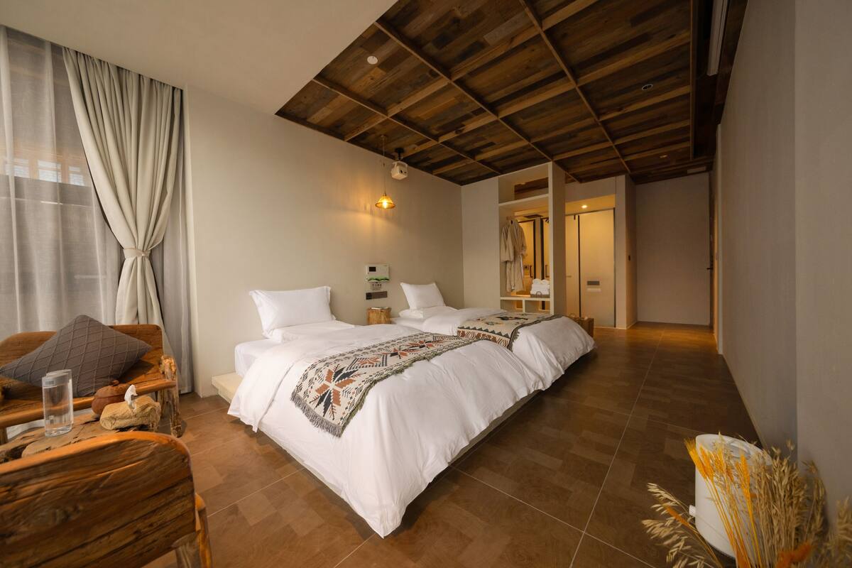 Quarto espaçoso com uma cama grande, teto de madeira e vista para um banheiro.