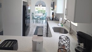 Una cocina moderna con una isla central, horno empotrado, cafetera y vistas al exterior.