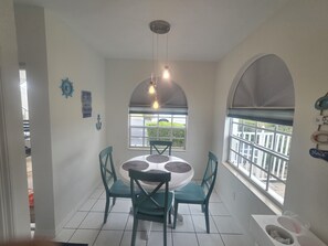A dining area with a round table, four chairs, and a hanging light fixture.