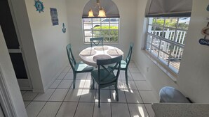 Un comedor con una mesa redonda, cuatro sillas y un ventanal con vistas al exterior.