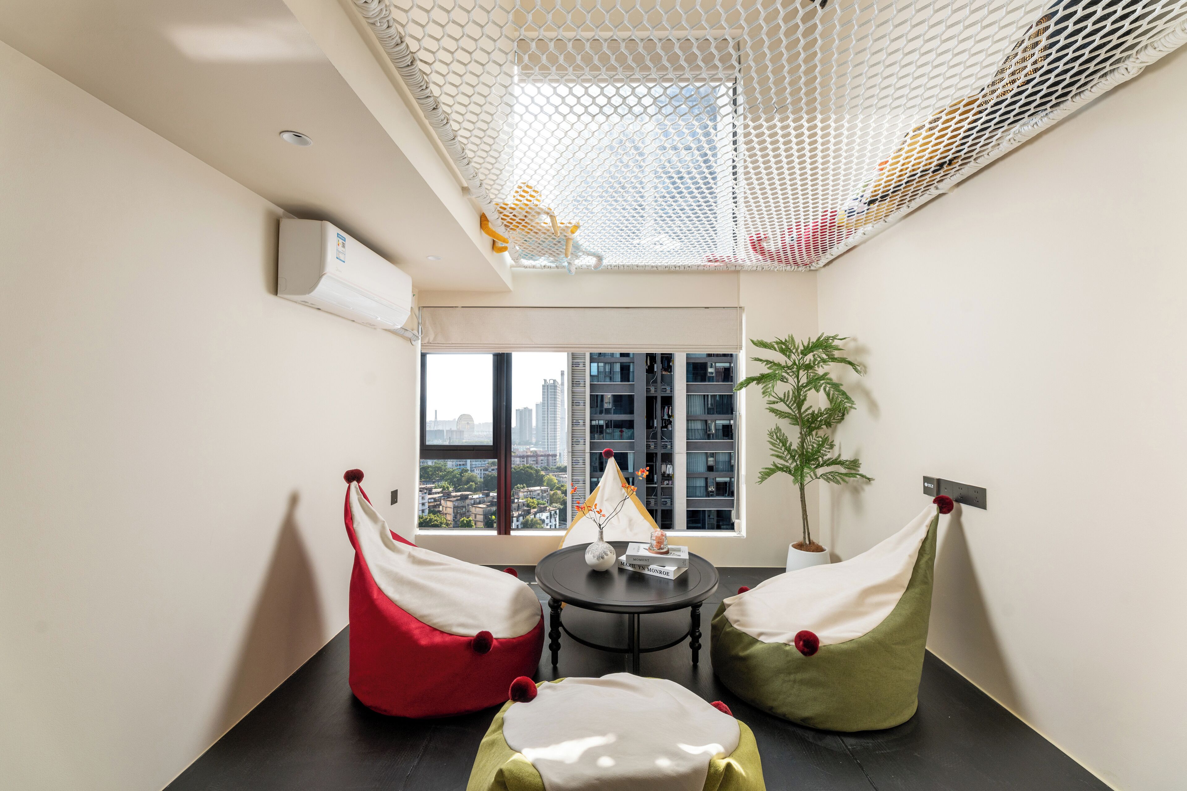 Una habitación moderna con vista a la ciudad, una mesita pequeña y dos pufs.