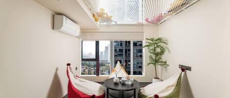 Una habitación moderna con vista a la ciudad, una mesita pequeña y dos pufs.