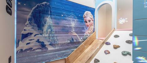 A children's play area with a mural of a snowy landscape and a slide.