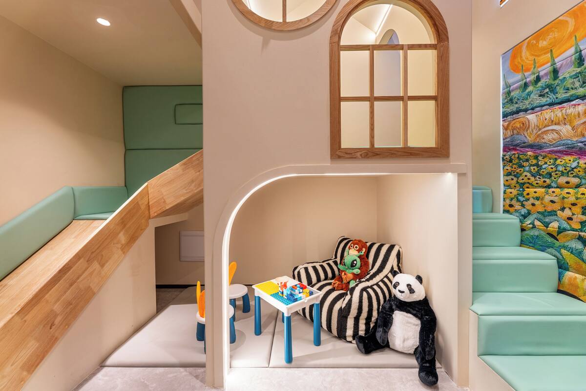 A children's play area with a slide, a table with toys, and a panda plush toy.