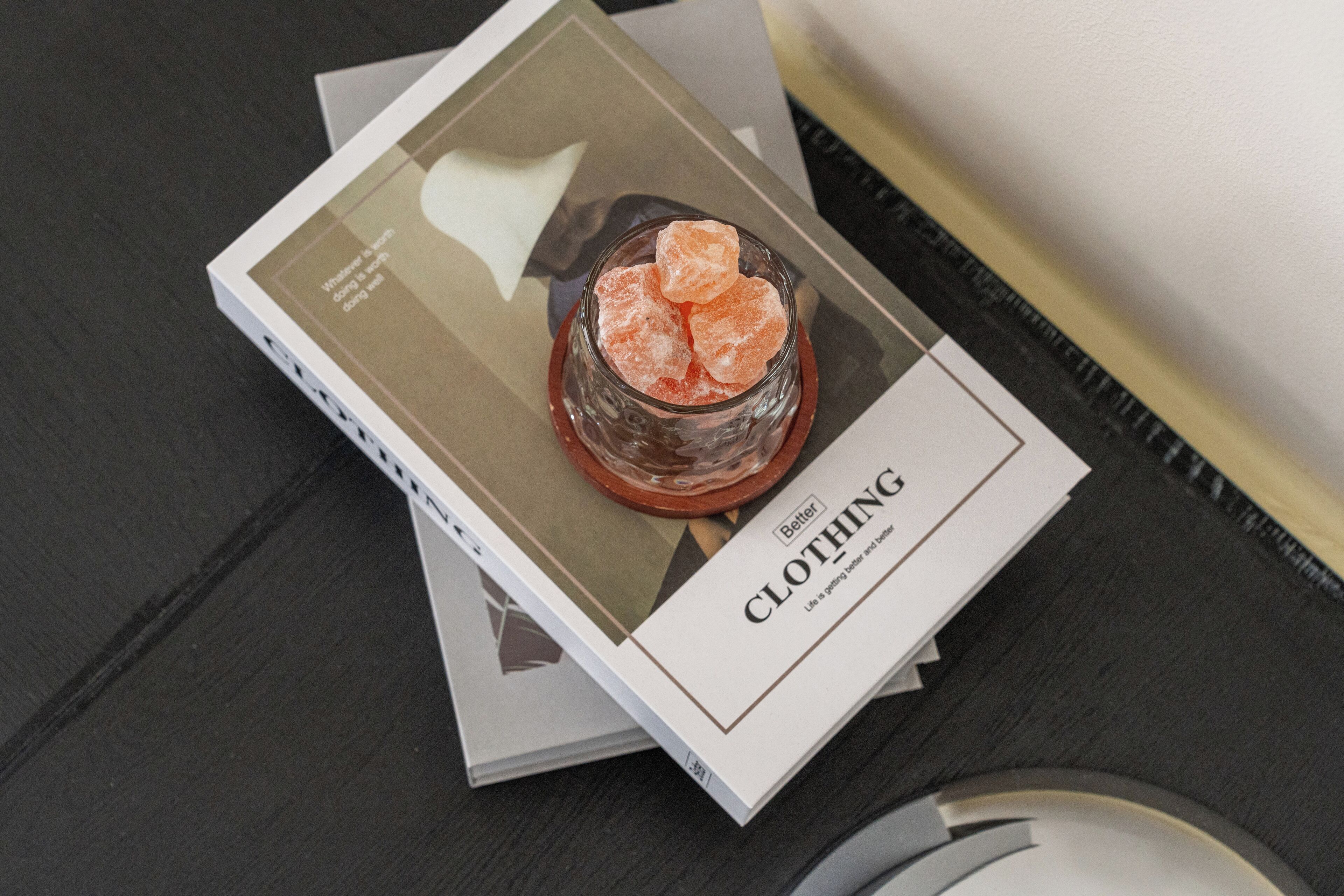 Un livre intitulé « Better Clothing », sur lequel repose un verre rempli de glaçons, le tout posé sur une surface en bois sombre.