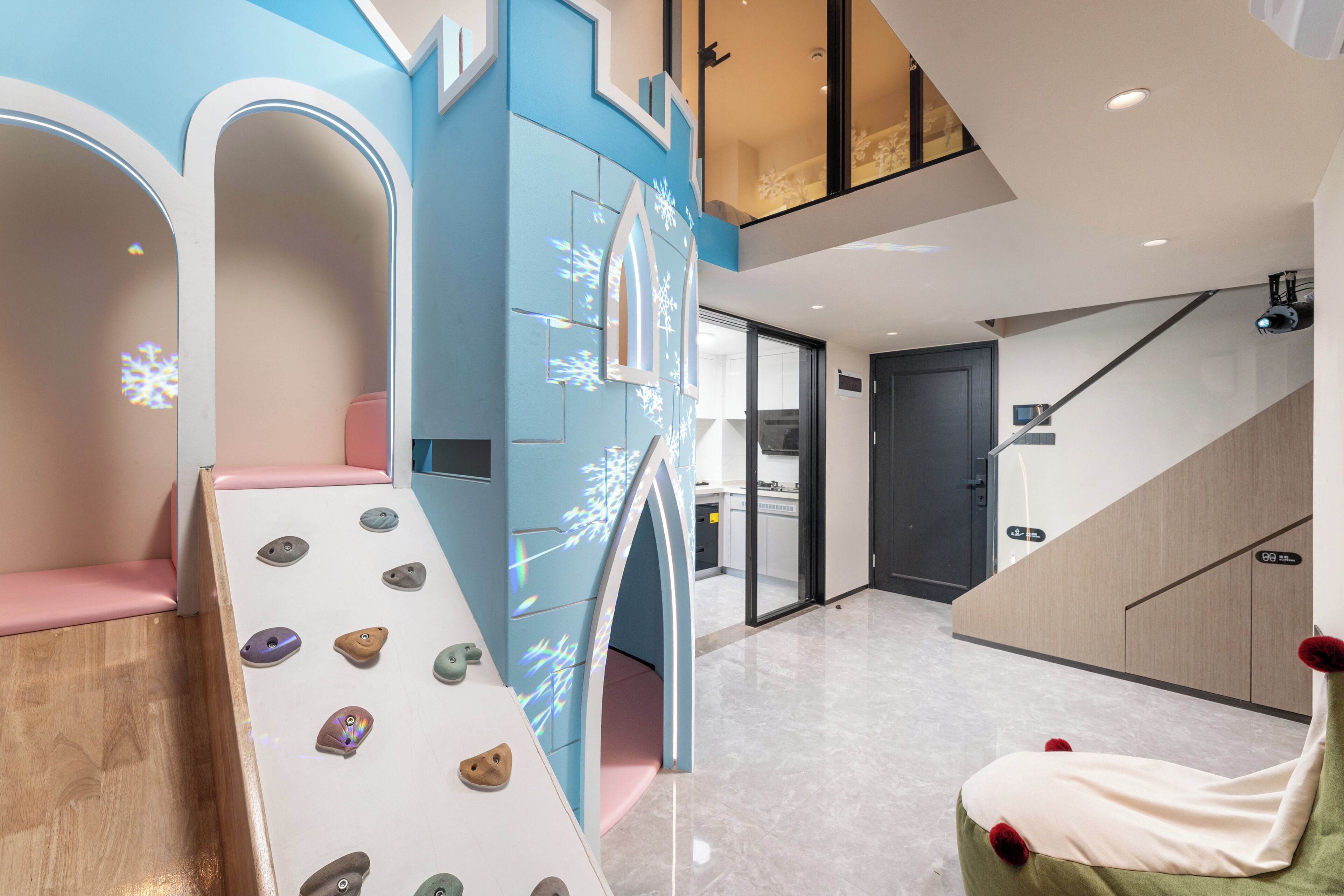 Un interior moderno con una pared de escalar, una zona de estar con cojines verdes y una escalera.
