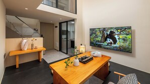 A modern living room with a wooden table, a TV displaying a panda, and a staircase. - GTOOO Hotel (Guangzhou)