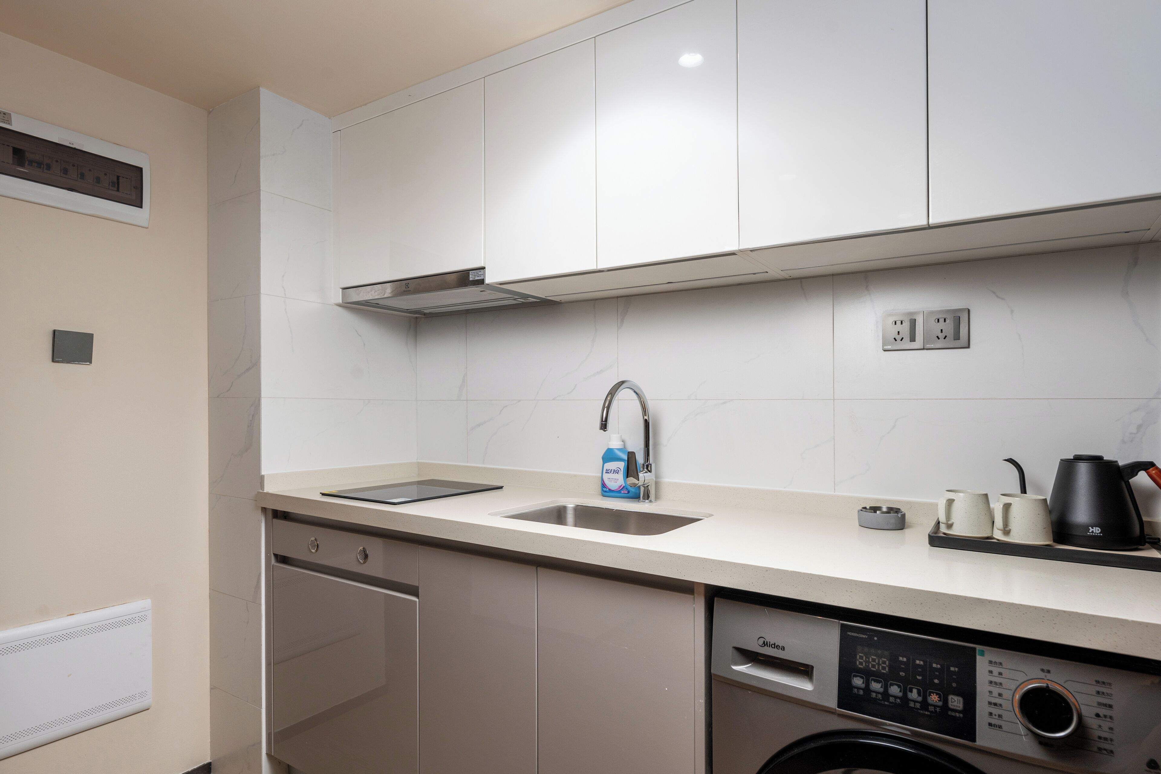 Een moderne keuken met een vaatwasser, een inbouwoven, een spoelbak en een koffiezetapparaat.