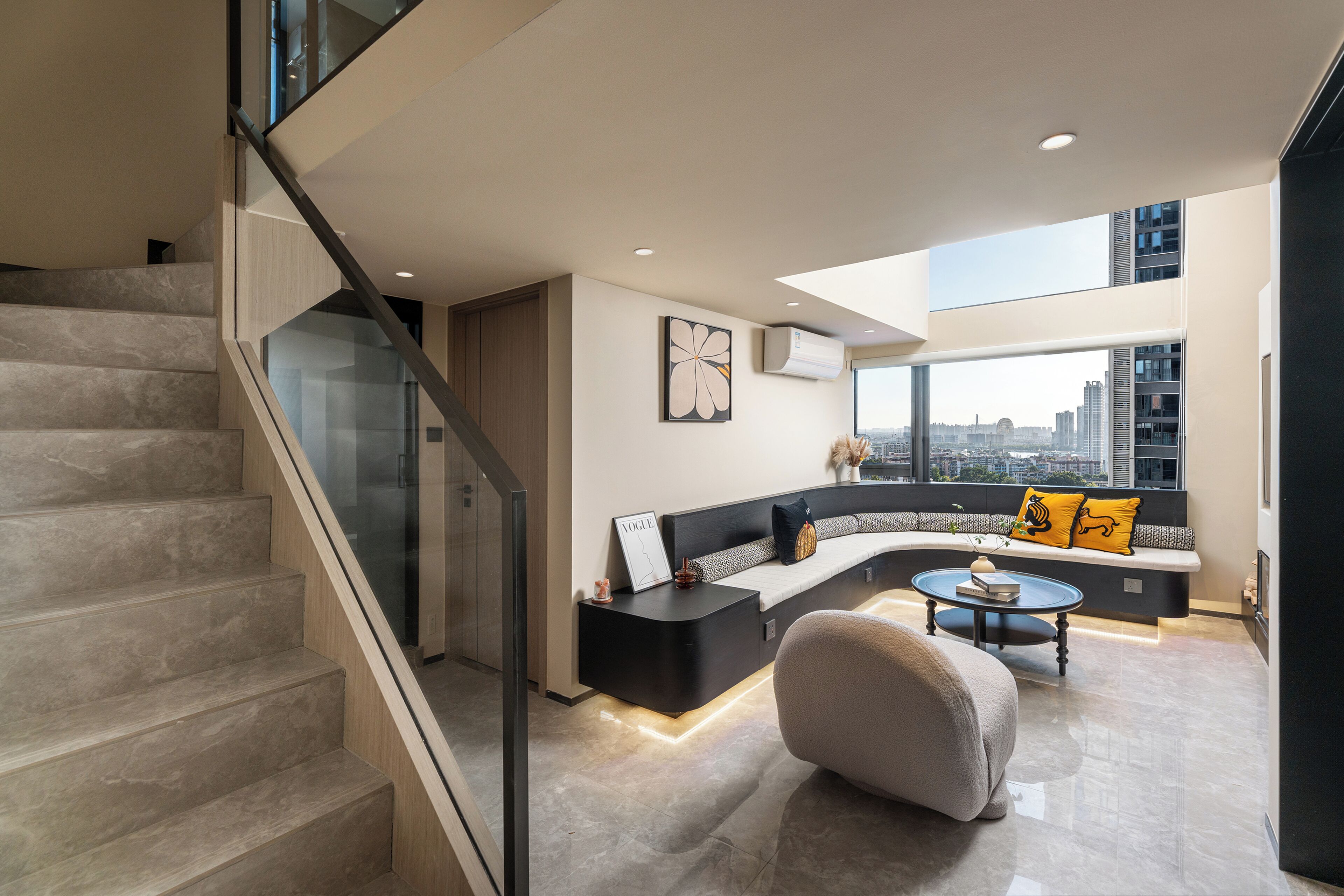 A modern living room with a curved sofa, a coffee table, and a staircase.