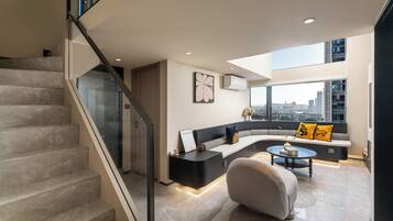 A modern living room with a curved sofa, a coffee table, and a staircase.