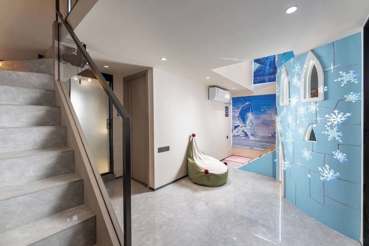 A modern interior with a staircase, a bean bag chair, and a wall with snowflake decorations.