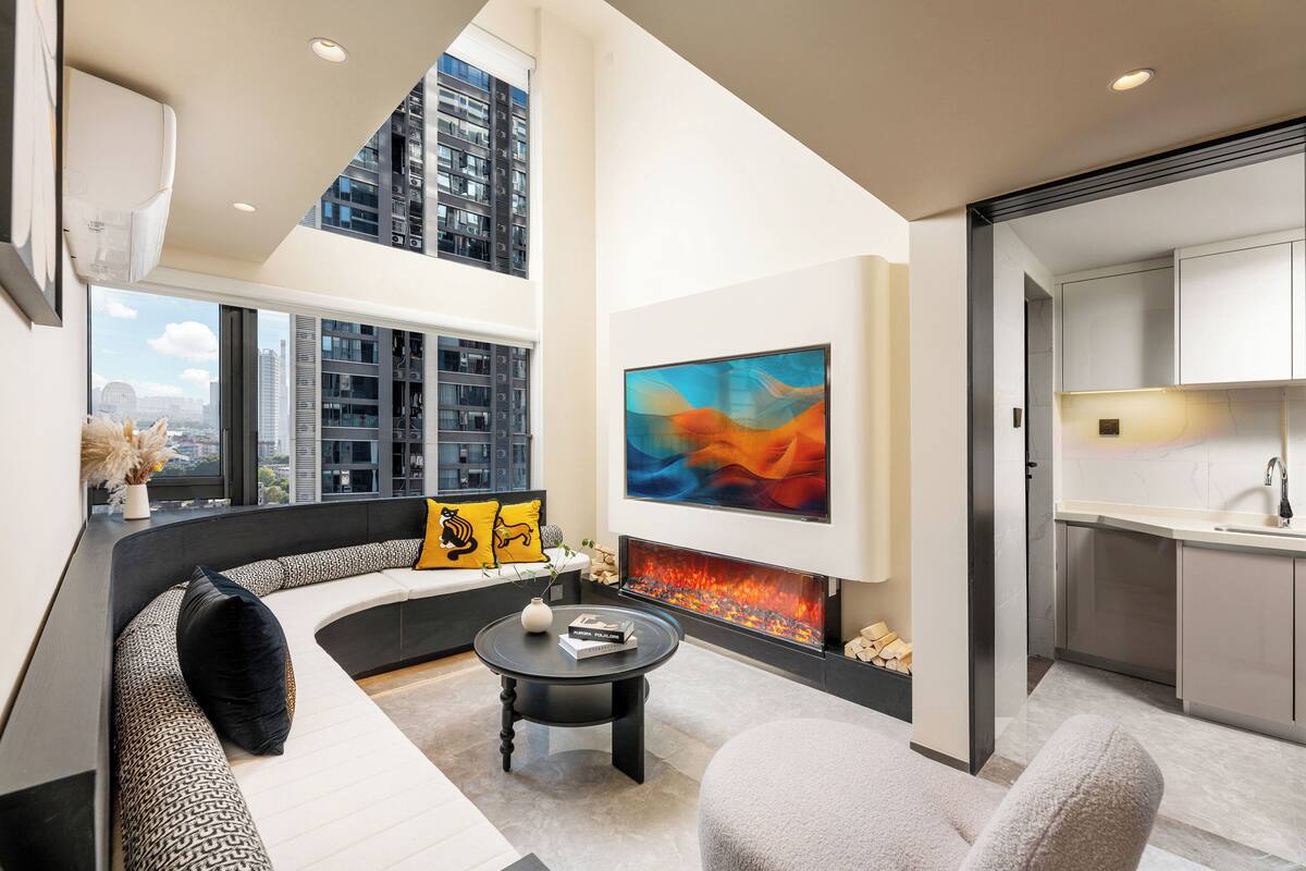 A modern living room with a curved sofa, a fireplace, and a large abstract painting.