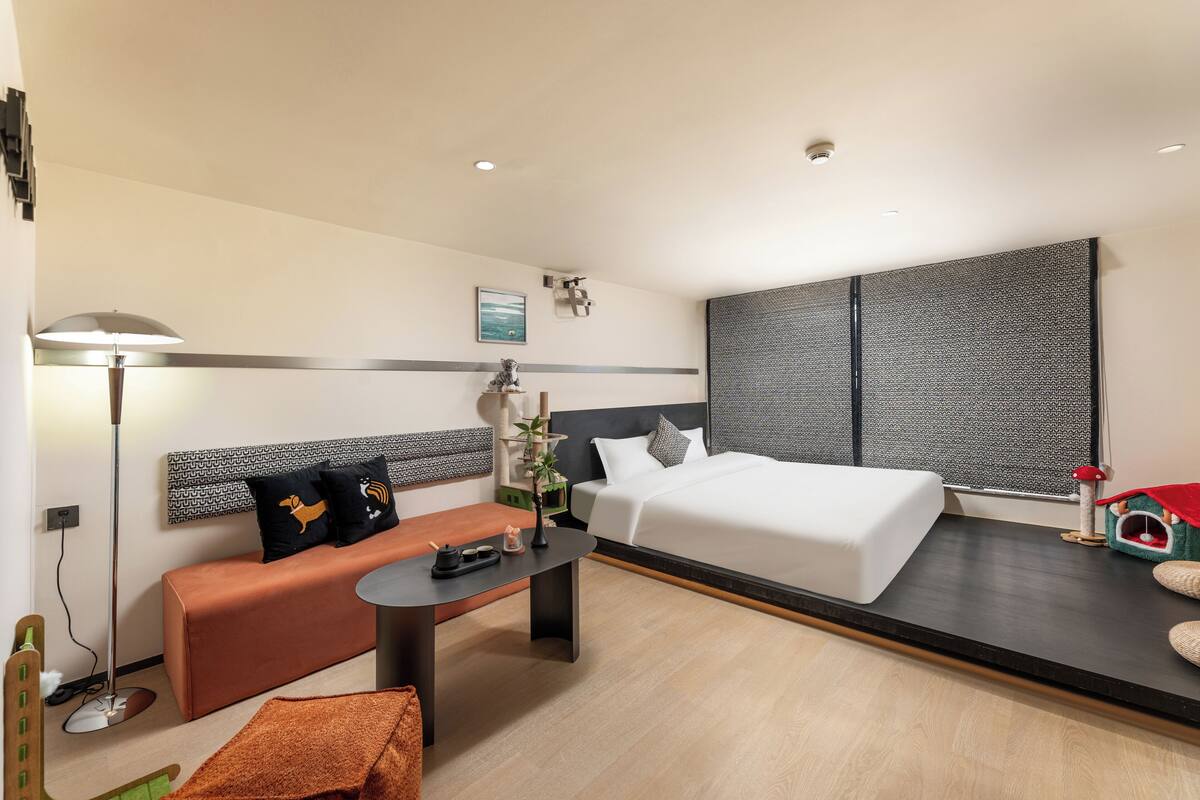 A modern hotel room with a bed, sofa, and desk.