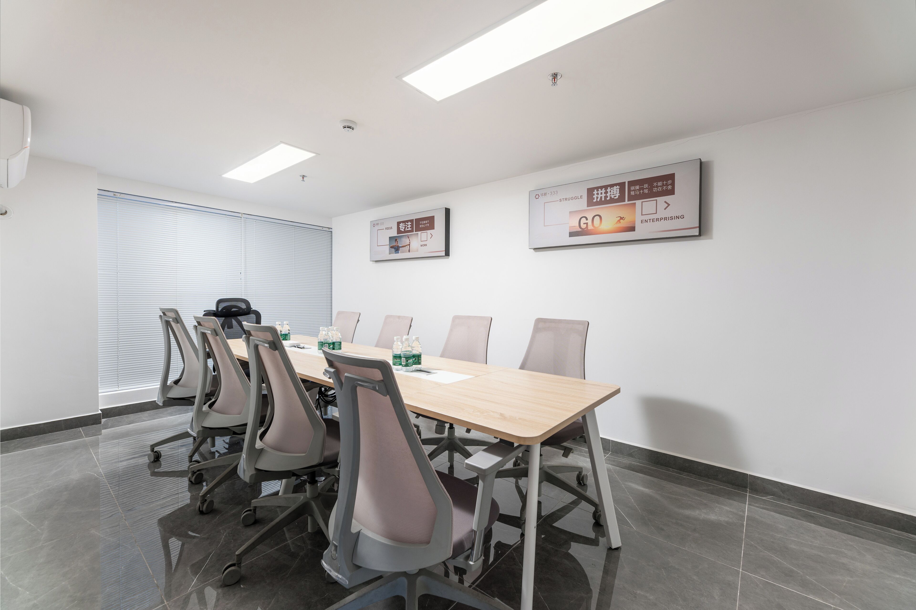 Une salle de conférence avec une longue table, six chaises et deux affiches au mur.