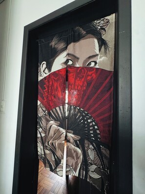 A room with a large, ornate mirror reflecting a traditional fan and a person's face. - Youkoso Hostel Floripa (Florianópolis)