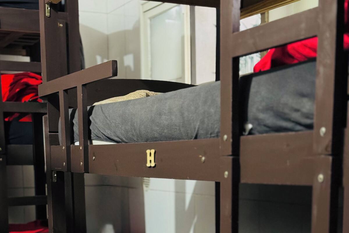 Un lit superposé avec une lettre « H » sur la tête de lit, une couverture bleue et des oreillers rouges.