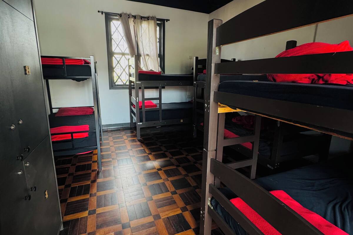 Une chambre de dortoir avec des lits superposés, une armoire et une fenêtre avec des rideaux.