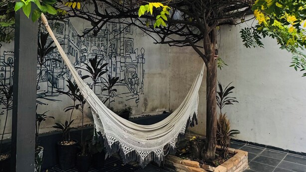 A hammock under a tree, a tiled floor, and a mural on the wall. - Youkoso Hostel Floripa (Florianópolis)