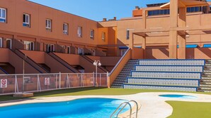 Un edificio moderno con piscina, escaleras exteriores y un cielo azul despejado.