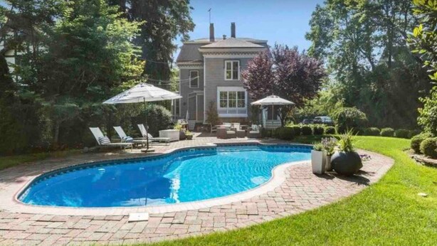 A swimming pool with a brick border, surrounded by a well-maintained lawn and trees. - Spacious 5-bedroom house with pool and two office rooms in charming Montclair (Montclair)