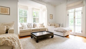 A spacious living room with a large sofa, a coffee table, and a fireplace. - Spacious 5-bedroom house with pool and two office rooms in charming Montclair (Montclair)