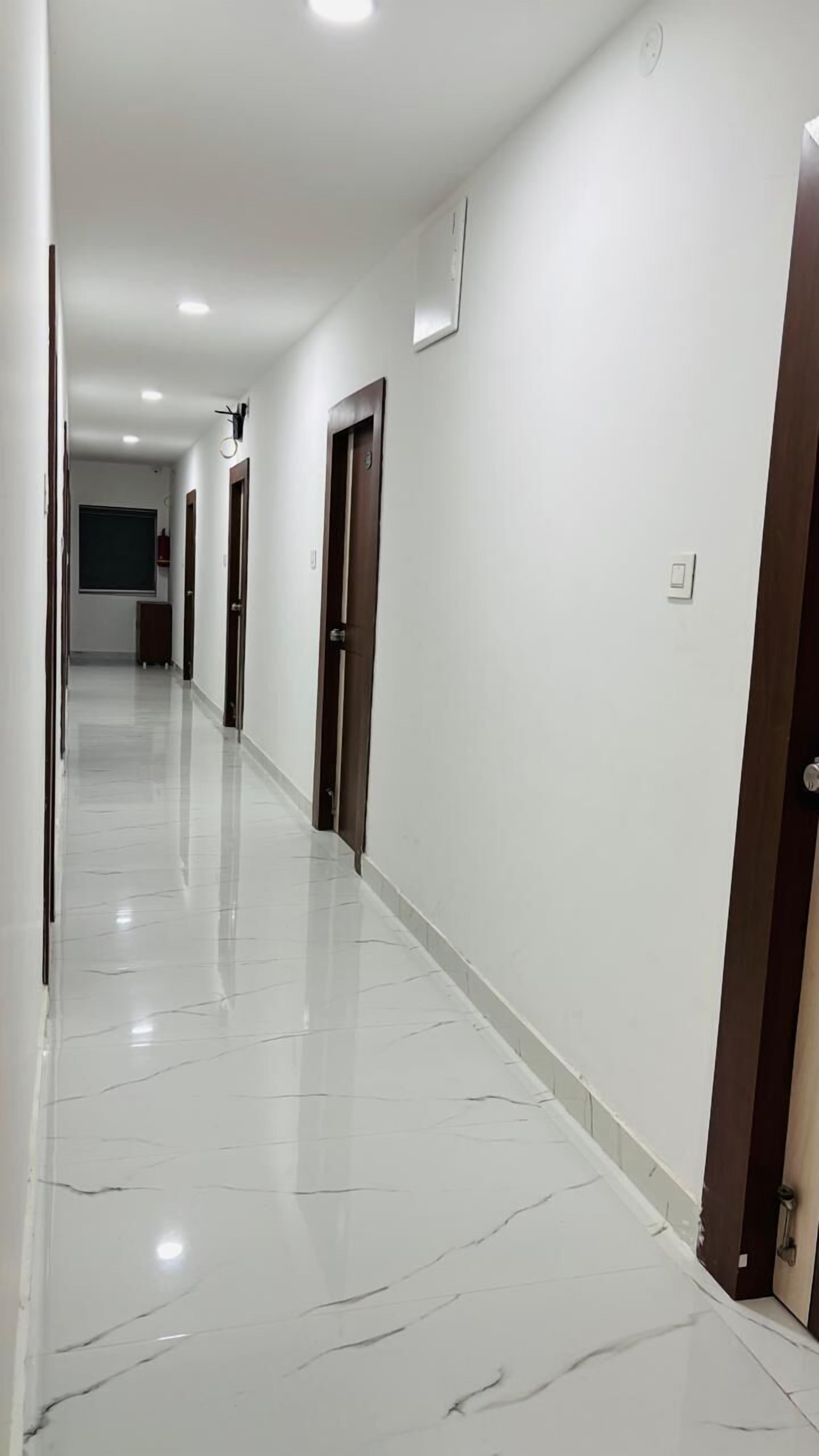 A long, narrow hallway with white walls and a shiny, marble floor.