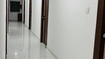 A long, narrow hallway with white walls and a shiny, marble floor.