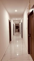 A long, narrow hallway with white walls and a shiny tiled floor.