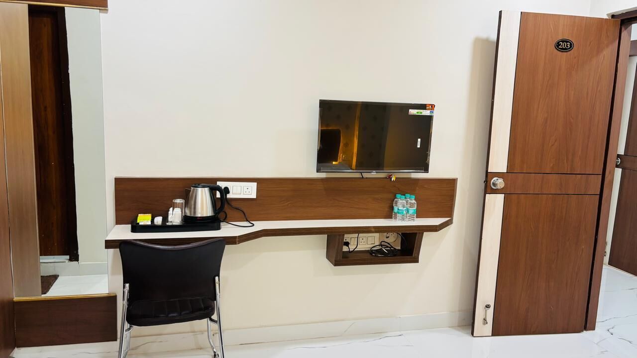 Una camera d'albergo compatta con una scrivania in legno, una televisione, un minibar e un armadio.
