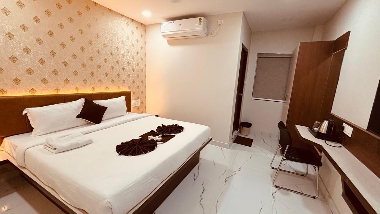 Ein Hotelzimmer mit einem Bett, einem Schreibtisch und einem Stuhl. An der Wand ist eine Klimaanlage angebracht.