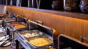 A buffet setup with various food items and utensils. - HOTEL MITHRA GRAND (Hyderabad)