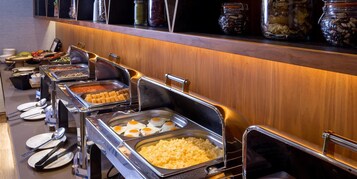 A buffet setup with various food items and utensils.