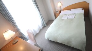 A hotel room with a bed, a bedside lamp, a nightstand, and a window with curtains. - Plaza in Mizusawa (Oshu)