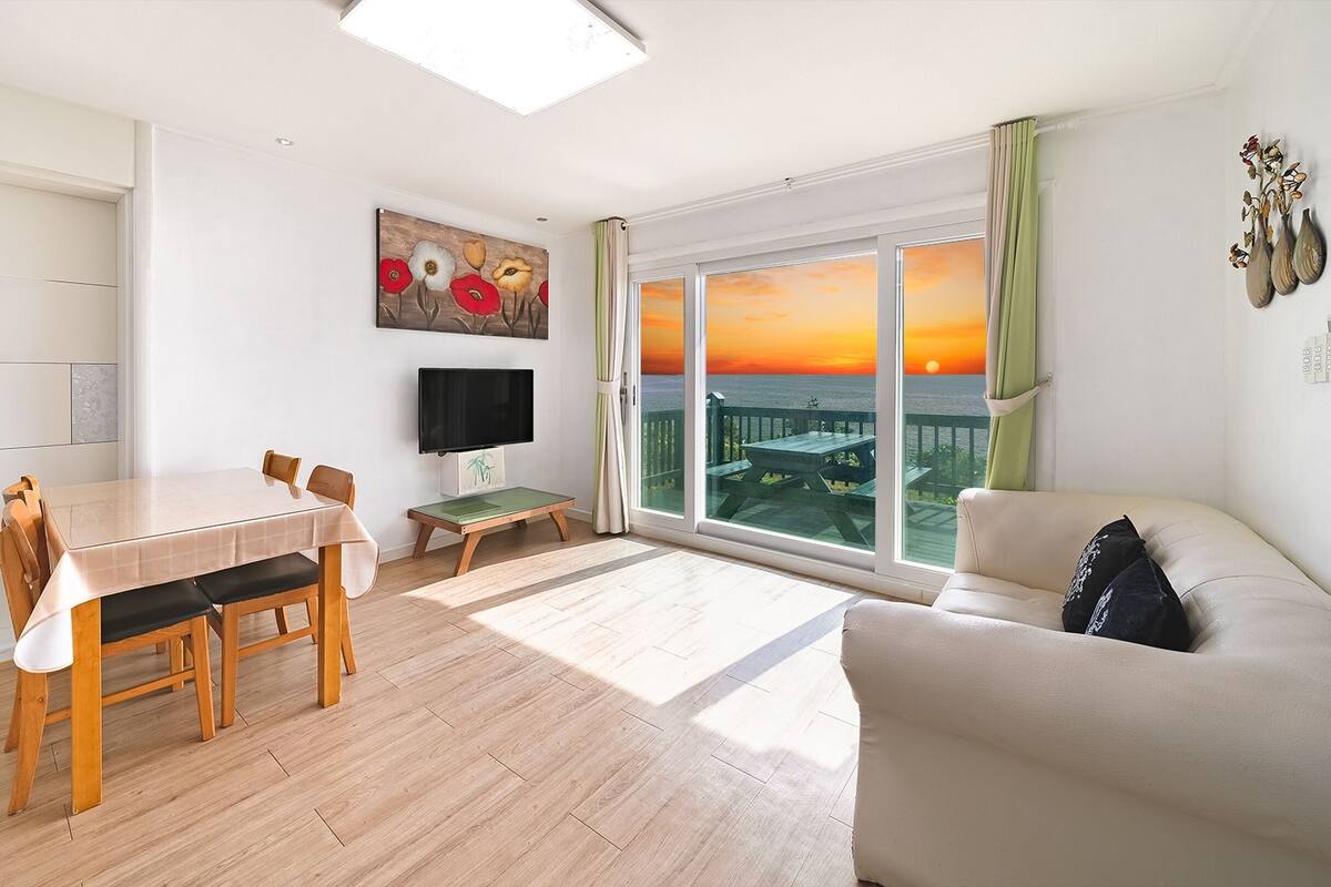Ein modernes Wohnzimmer mit einem Holzesstisch, einer Couch und einem Fernseher.