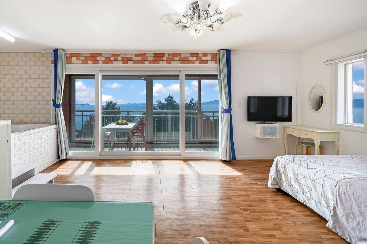 Ein Schlafzimmer mit Balkon, Fernseher und Schreibtisch.