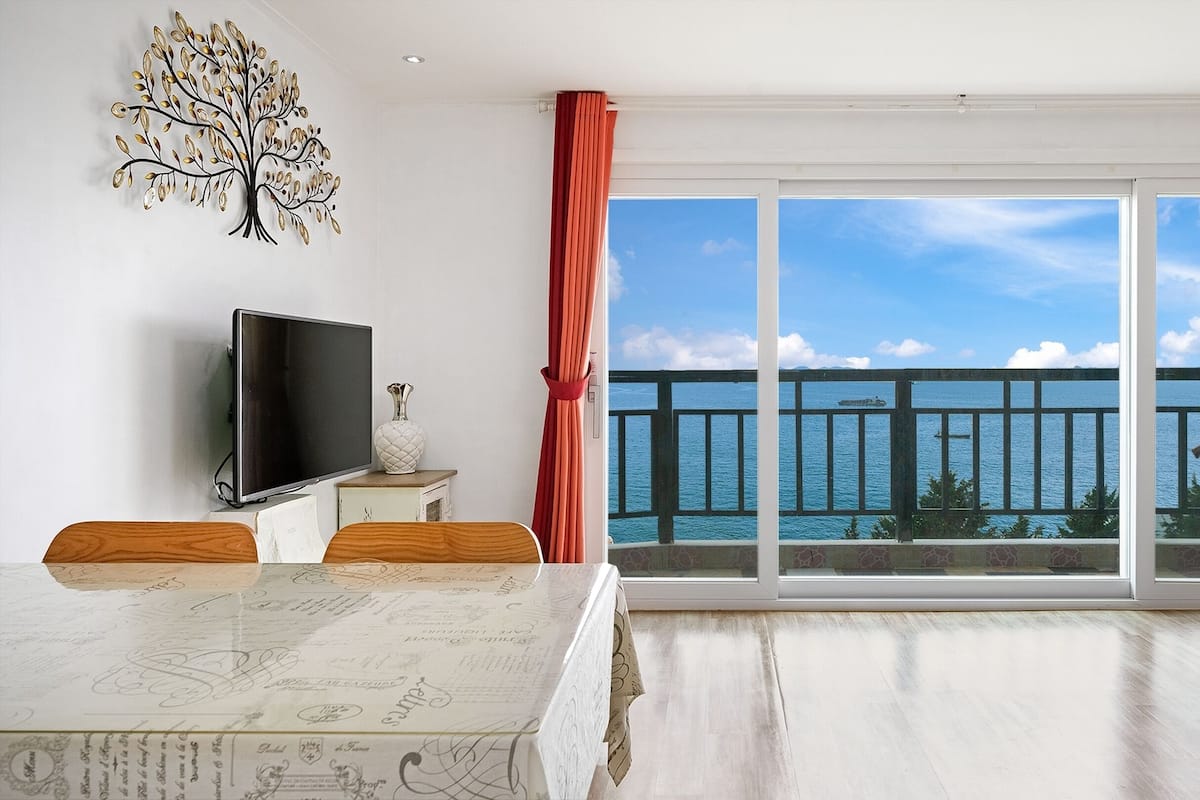 Ein geräumiges Zimmer mit einer großen Schiebeglasdoor zum Balkon mit Meerblick.