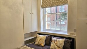 Une chambre à coucher avec un lit, deux oreillers, une fenêtre et une armoire.