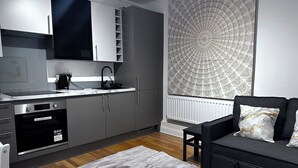 Une cuisine moderne avec des meubles gris, une hotte noire et un four encastré.