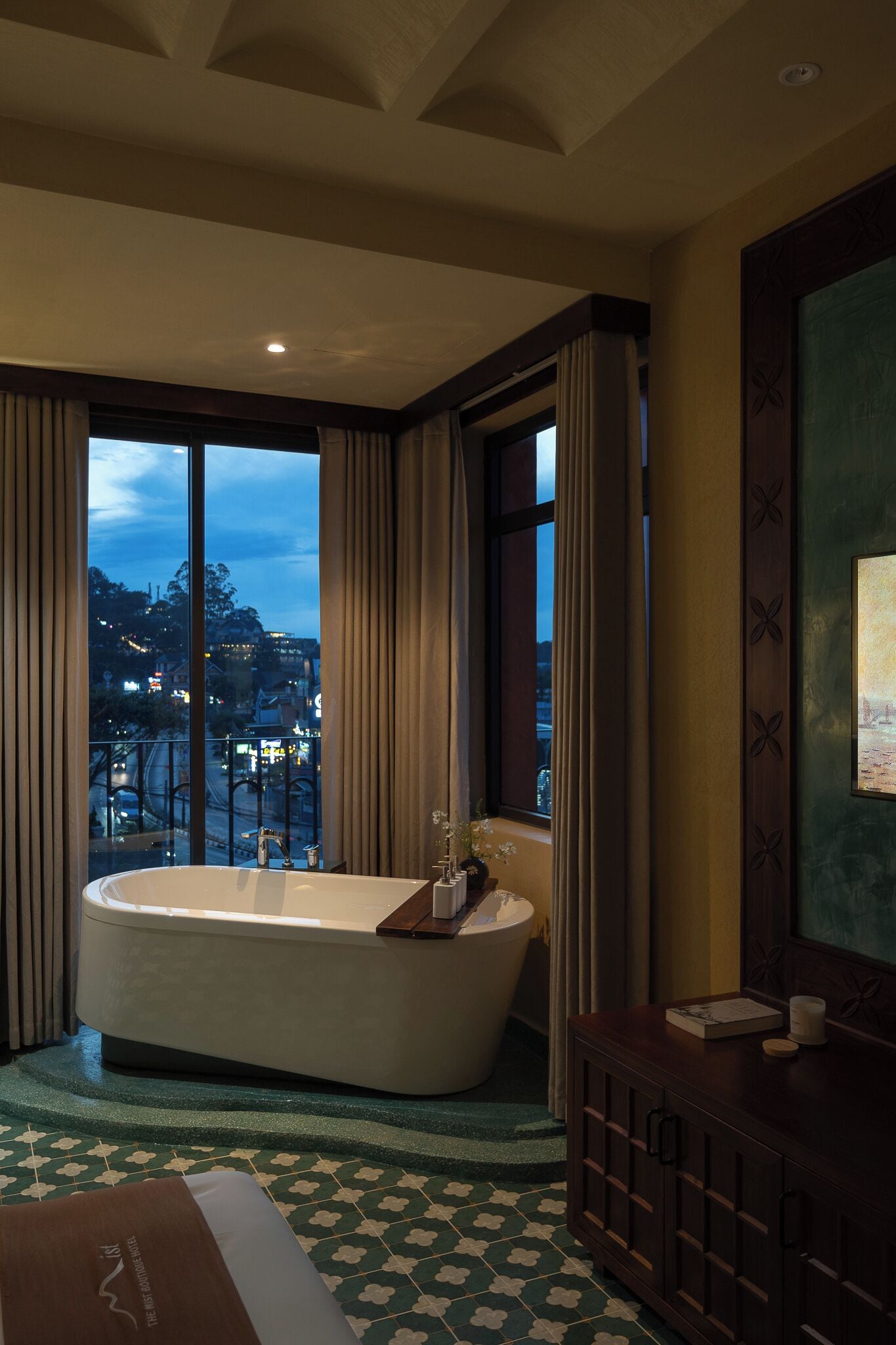 A modern bathroom with a freestanding bathtub, a wooden vanity, and a large window offering a city view.