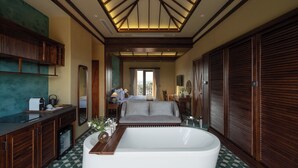 A spacious bathroom with a large bathtub, a vanity with a mirror, and a seating area with a sofa.